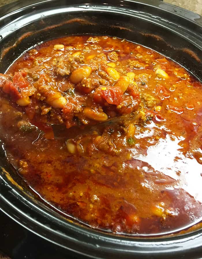Overhead shot of a slow cooker full to the top with chili.