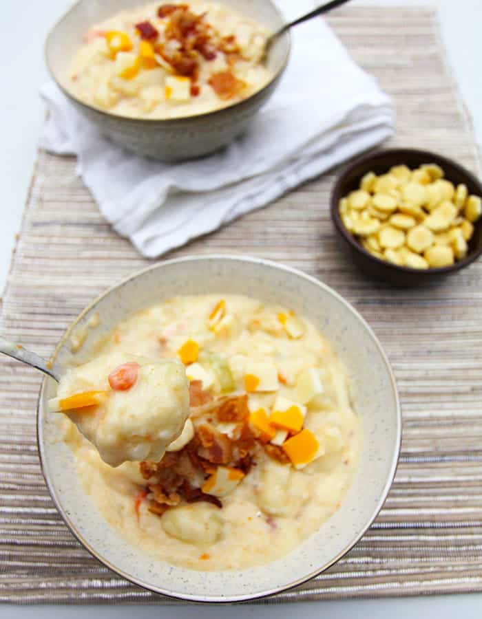 Two bowls of chunky loaded potato soup, on a placemat.