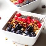 Side shot of two square bowls of Acai Smoothies, with fruit on top.