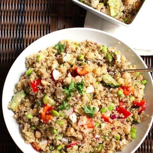 Overhead shot of a large bowl fo loaded veggie quinoa salad on a wicker tray.