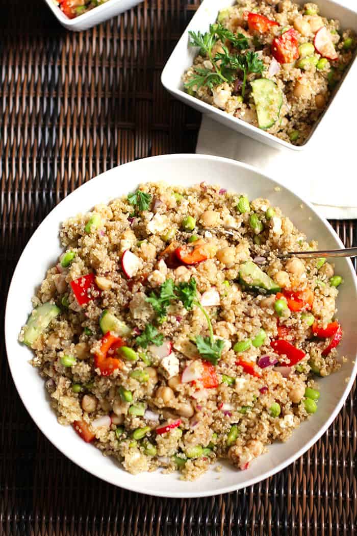 Overhead shot of a large bowl fo loaded veggie quinoa salad on a wicker tray.