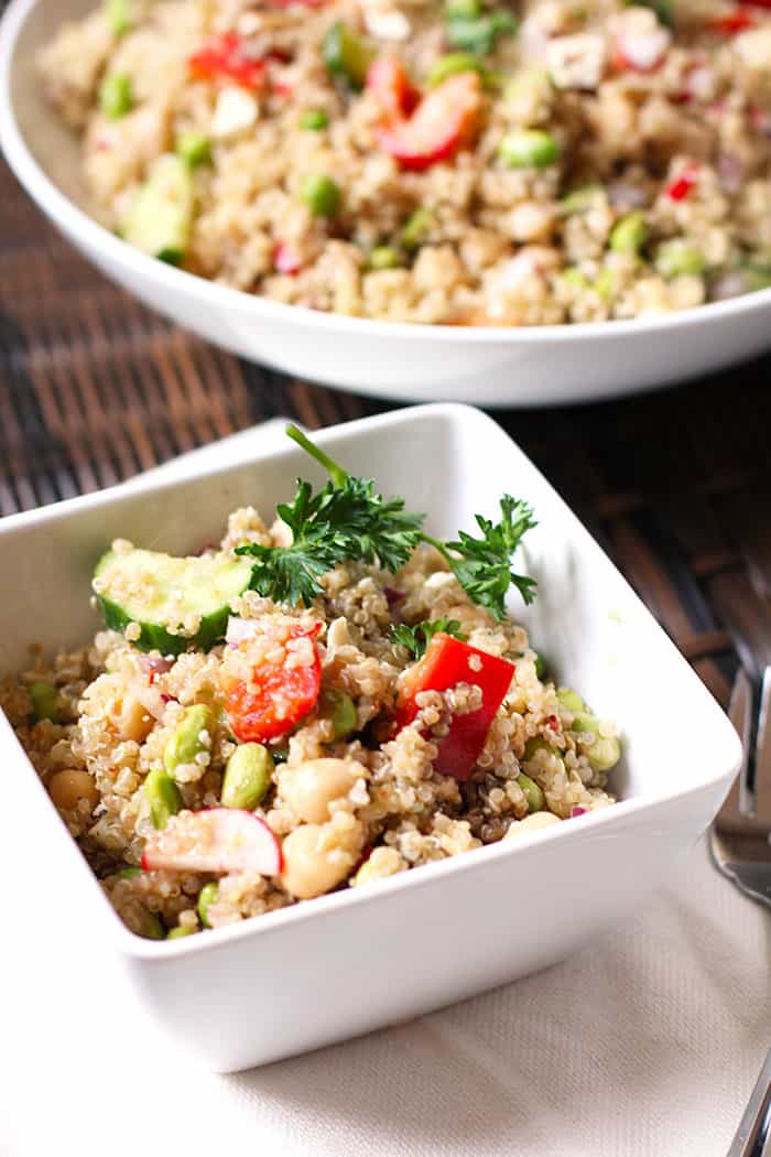 Side shot of a small square bowl of loaded quinoa salad.