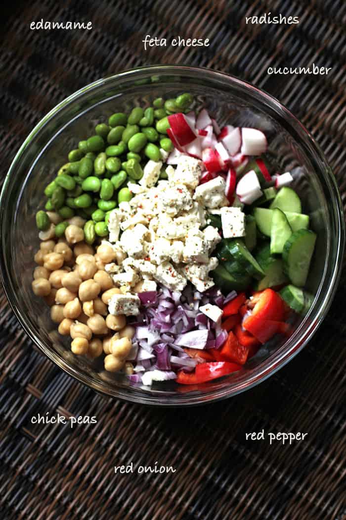 A glass bowl full of the quinoa salad, separated by ingredient.