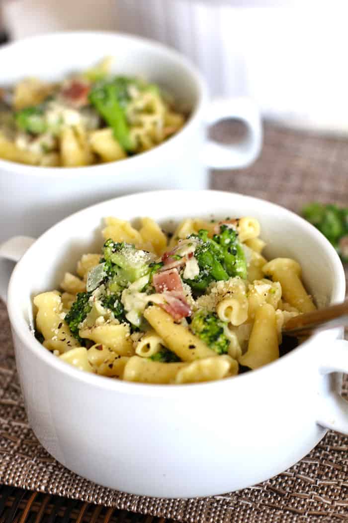 Side shot of two servings bowls of broccoli pasta with bacon.