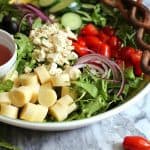 Overhead shot of a large bowl of Italian Hearts of Palm Salad, with ingredients in sections and two wooden spoons.