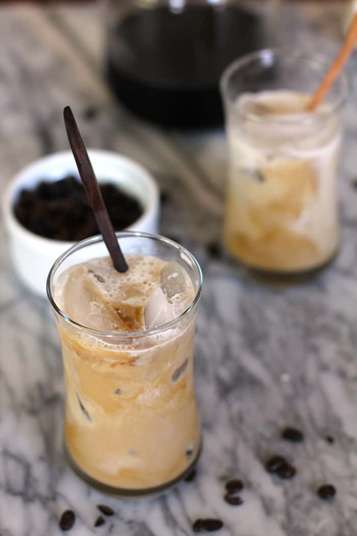 Side view of two cups of cold brew coffee, with stir sticks.