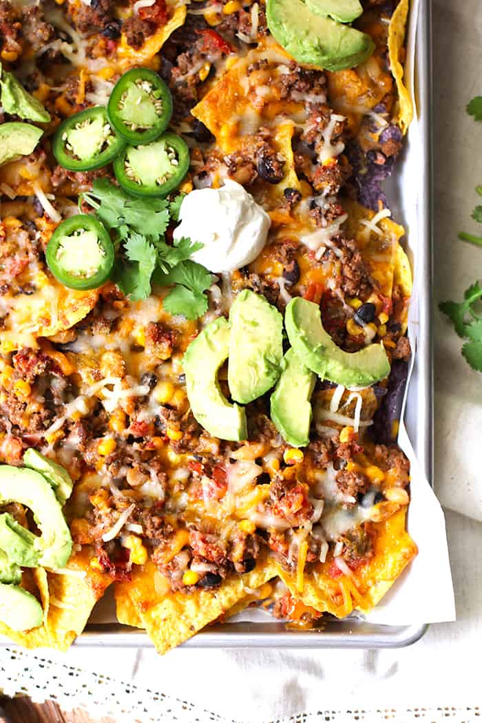 Close up shot of a corner of a sheet pan of beef and bean nachos.