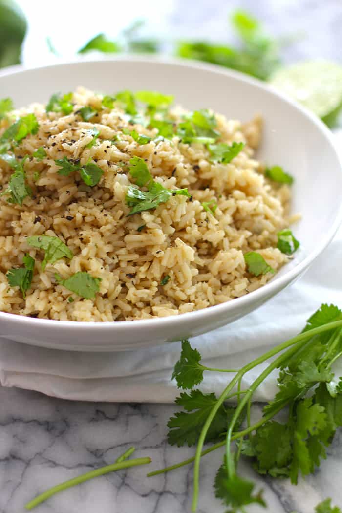 Side view of a white bowl of cilantro lime rice, on a gray background.