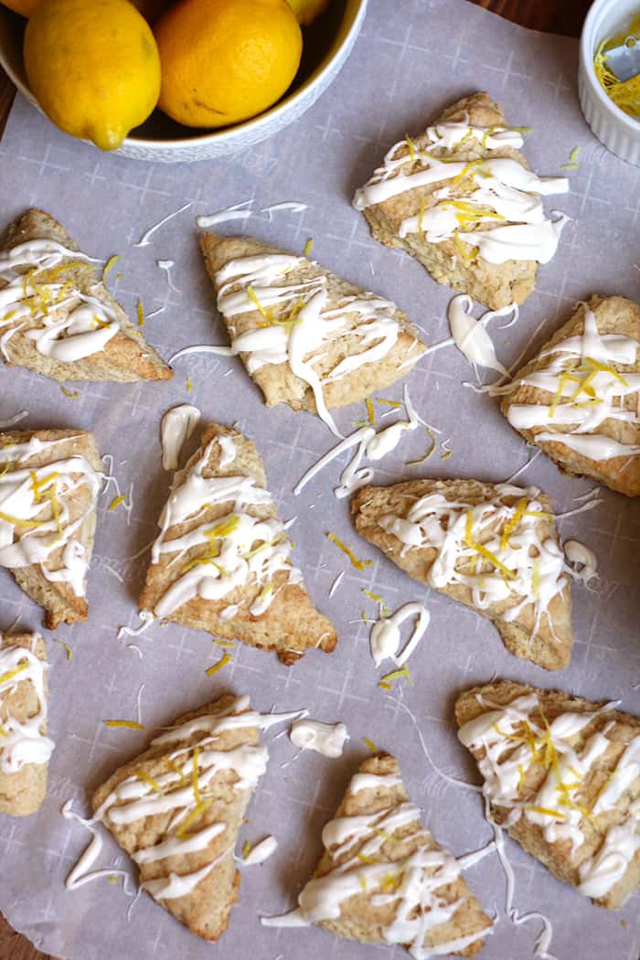 Overhead view of a bunch of petite lemon scones, on white parchment paper.