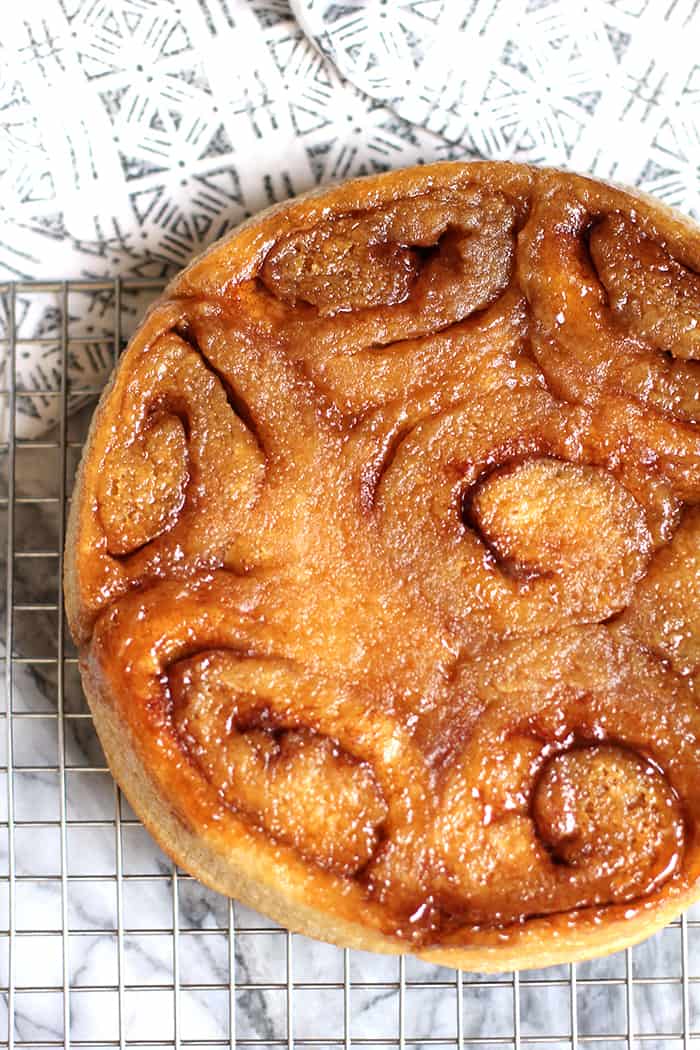 Overhead shot of caramel rolls, on a wire cooling rack on a white and gray napkin.