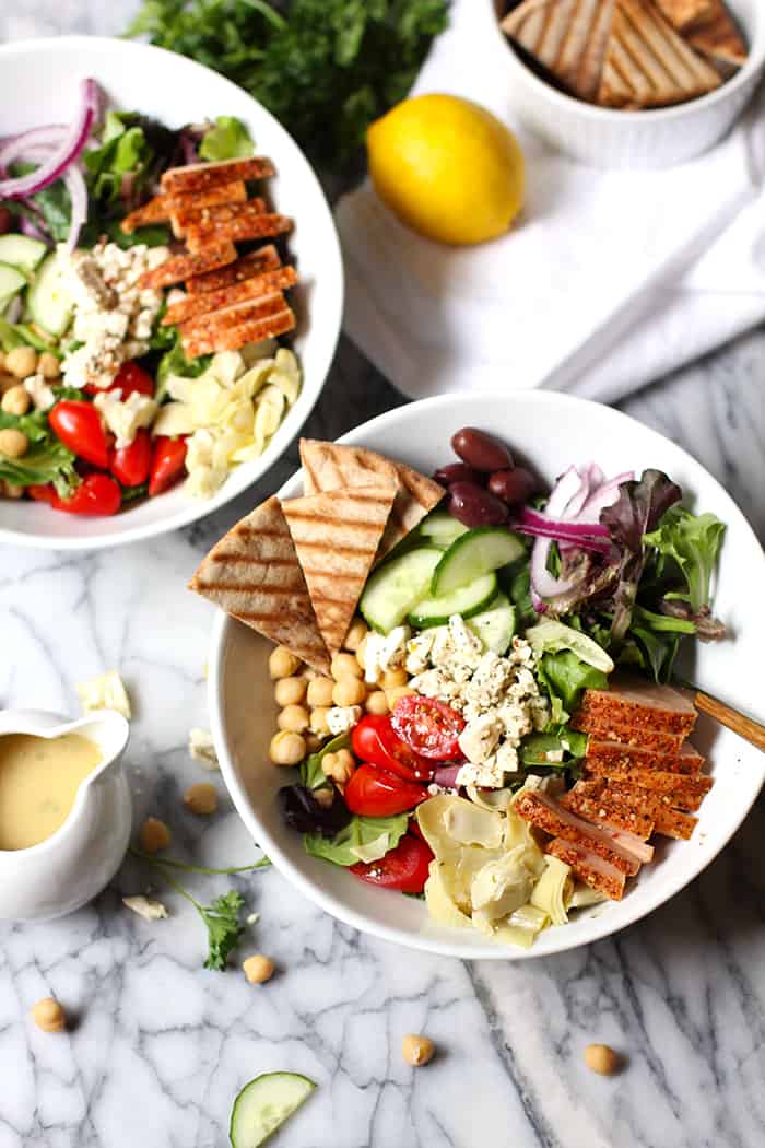 Overhead shot of two bowls of traditional Greek salads with smoked turkey breast.