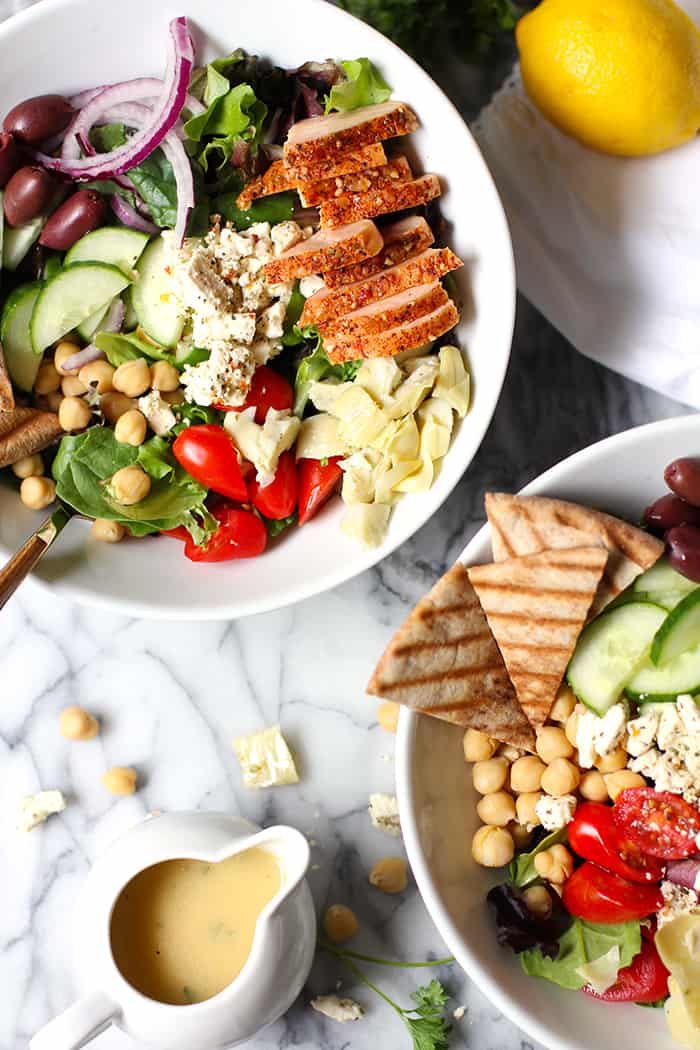 Closeup view of a traditional Greek salad with smoked turkey, and pita chips.