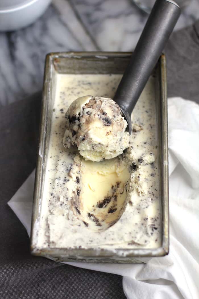 Overhead shot of a rectangular pan filled with cookies and cream ice cream, with an ice cream scoop scooping some out.