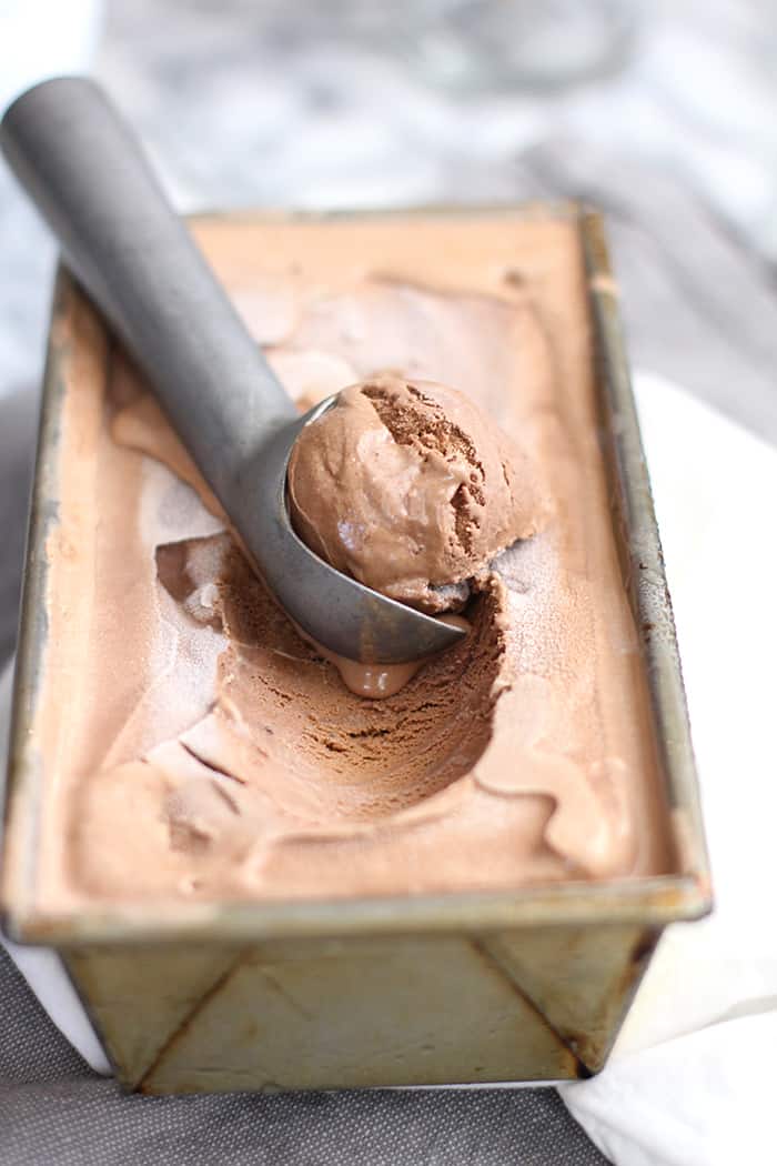A loaf pan full of double chocolate ice cream, with an ice cream scoop scooping some out.
