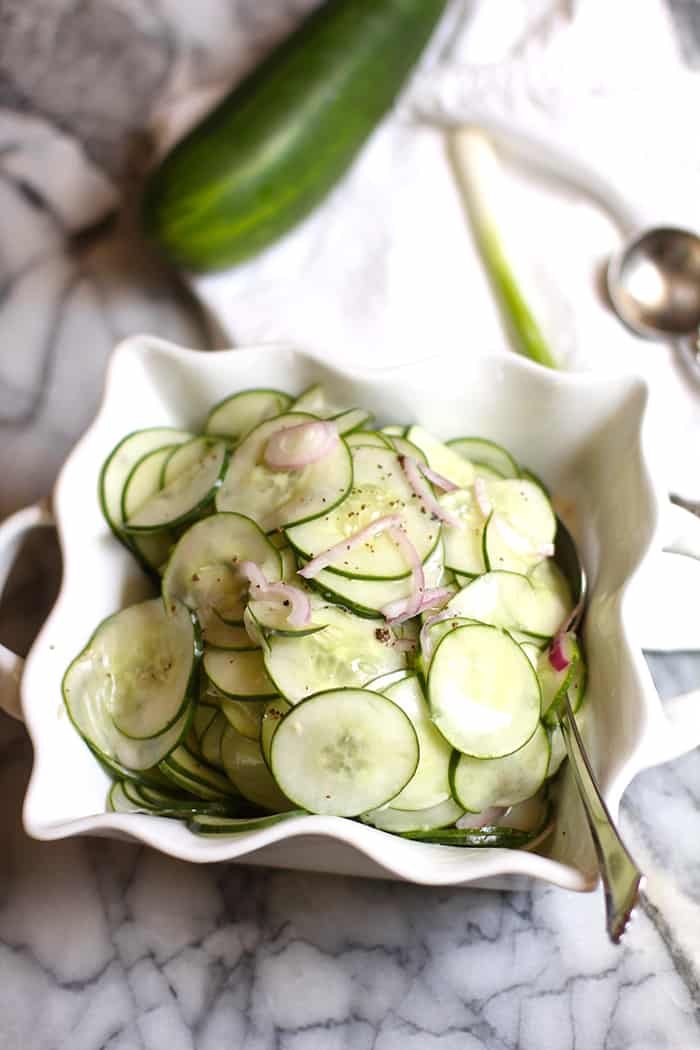 A bowl of fresh cucumbers on a gray tray.