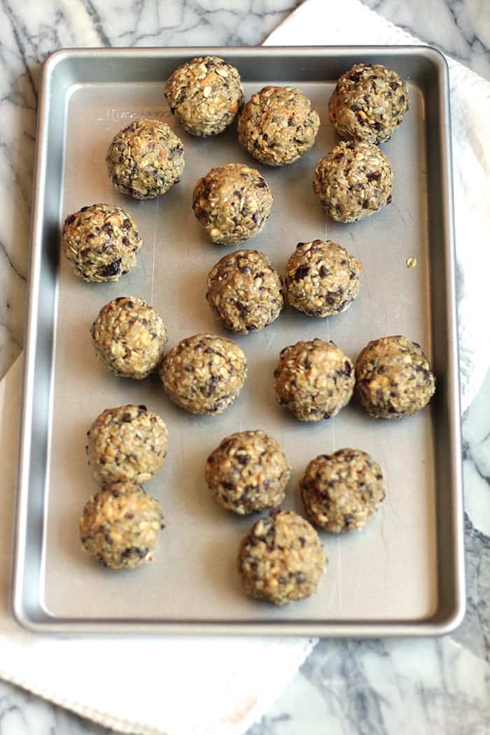 Overhead shot of peanut butter power balls on a baking sheet, on a white and gray background.