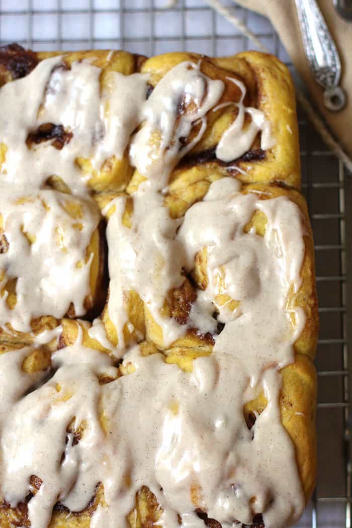 Close-up shot of pumpkin spice cinnamon rolls with a cinnamon glaze drizzled on top.