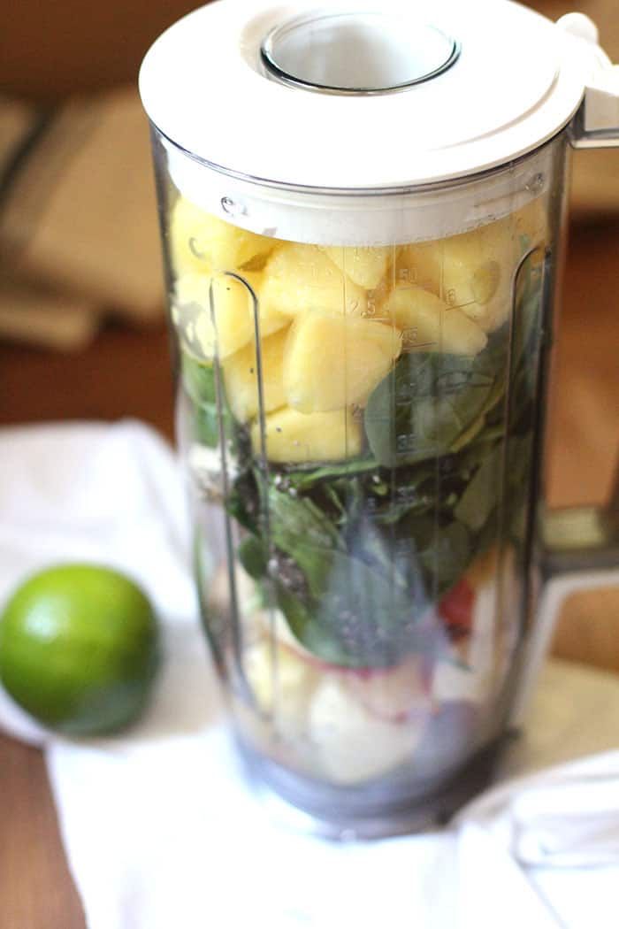 Side view of a blender holding all the ingredients for the green smoothie.