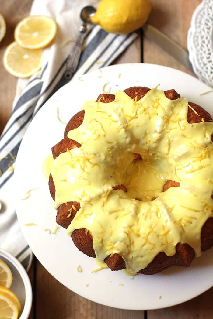 Overhead shot of a glazed lemon bundt cake on a white cake plate.