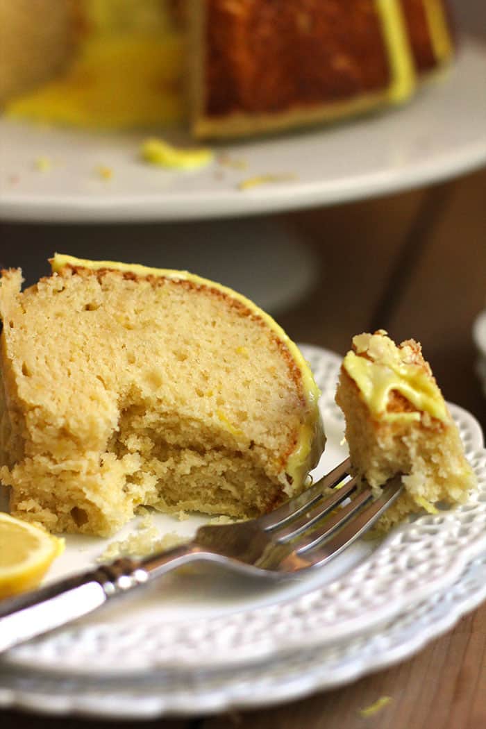 Side shot of a large slice of glazed lemon cake, with a big forkful out.