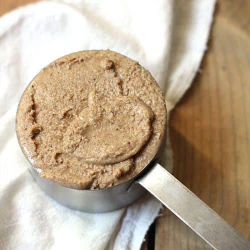 A one cup measuring cup full of homemade almond butter.