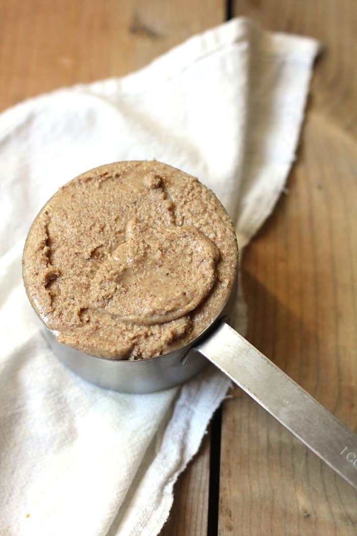 A one cup measuring cup full of homemade almond butter.