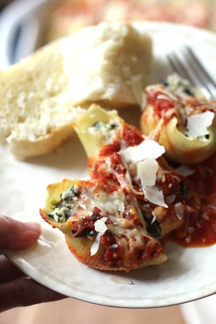 A plate of a couple of stuffed shells with some French bread.