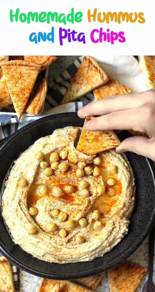 A hand dipping a pita bread into a bowl of homemade hummus.