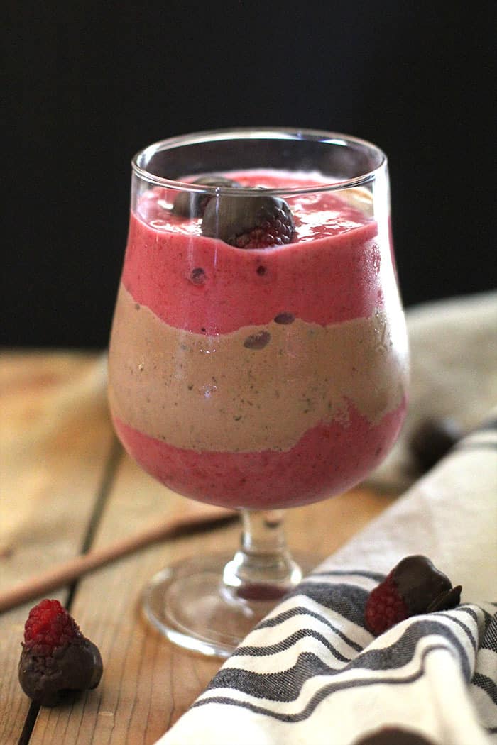 Side shot of a raspberry Nutella smoothie, on a wooden board.