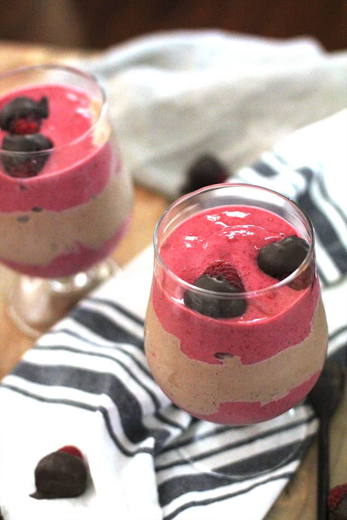 Overhead shot of two glasses of Raspberry Nutella Smoothies, with raspberries on top.