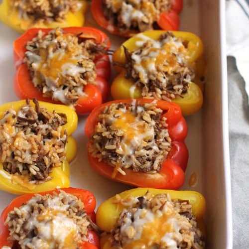 Side shot of a casserole dish of Mexican Beef Stuffed Peppers, with cheese on top.