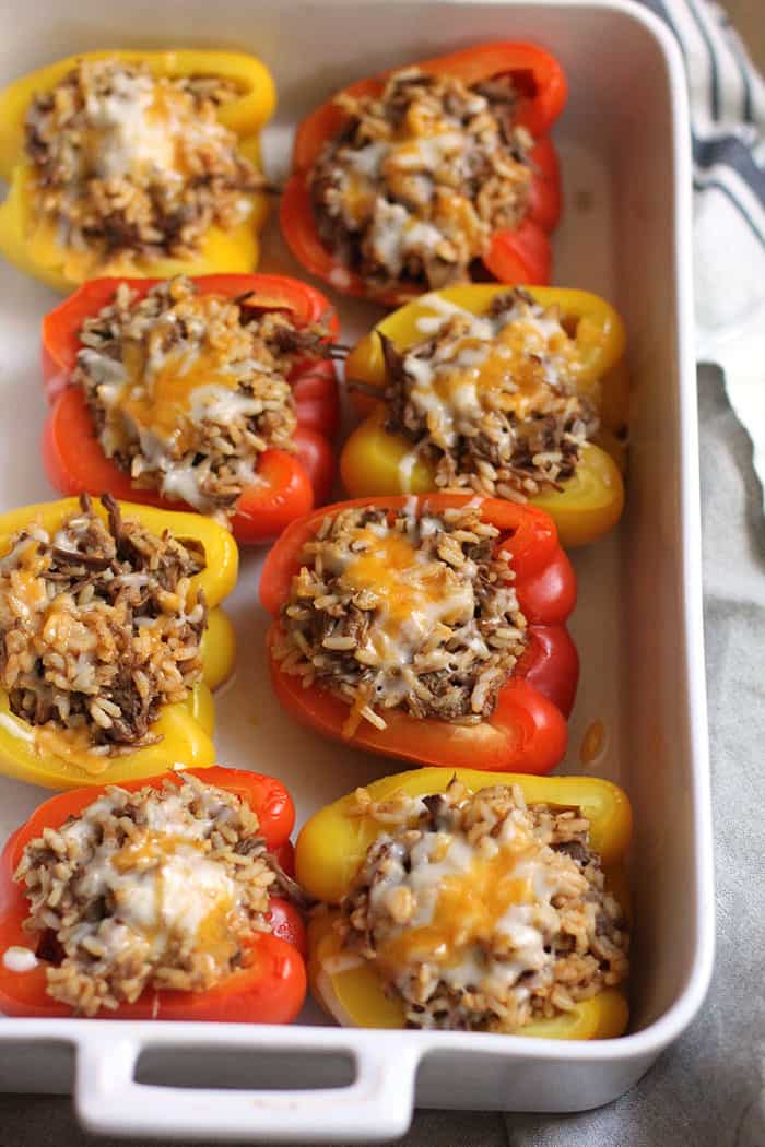 Side shot of a casserole dish of Mexican Beef Stuffed Peppers, with cheese on top.