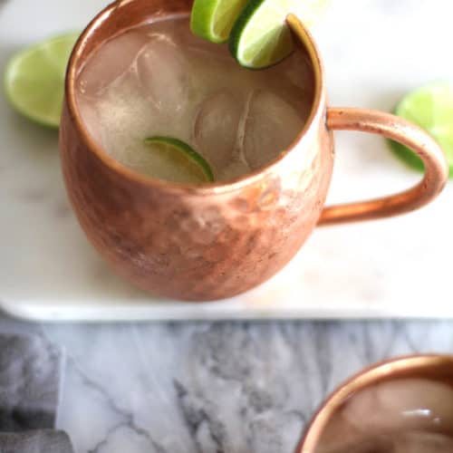 Overhead view of two classic Moscow mules in copper mugs with lime wedges.