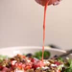 A drizzle of strawberry dressing over a strawberry bacon salad.