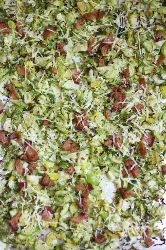 An overhead shot of a baking sheet of cooked, shaved Brussels sprouts and bacon.
