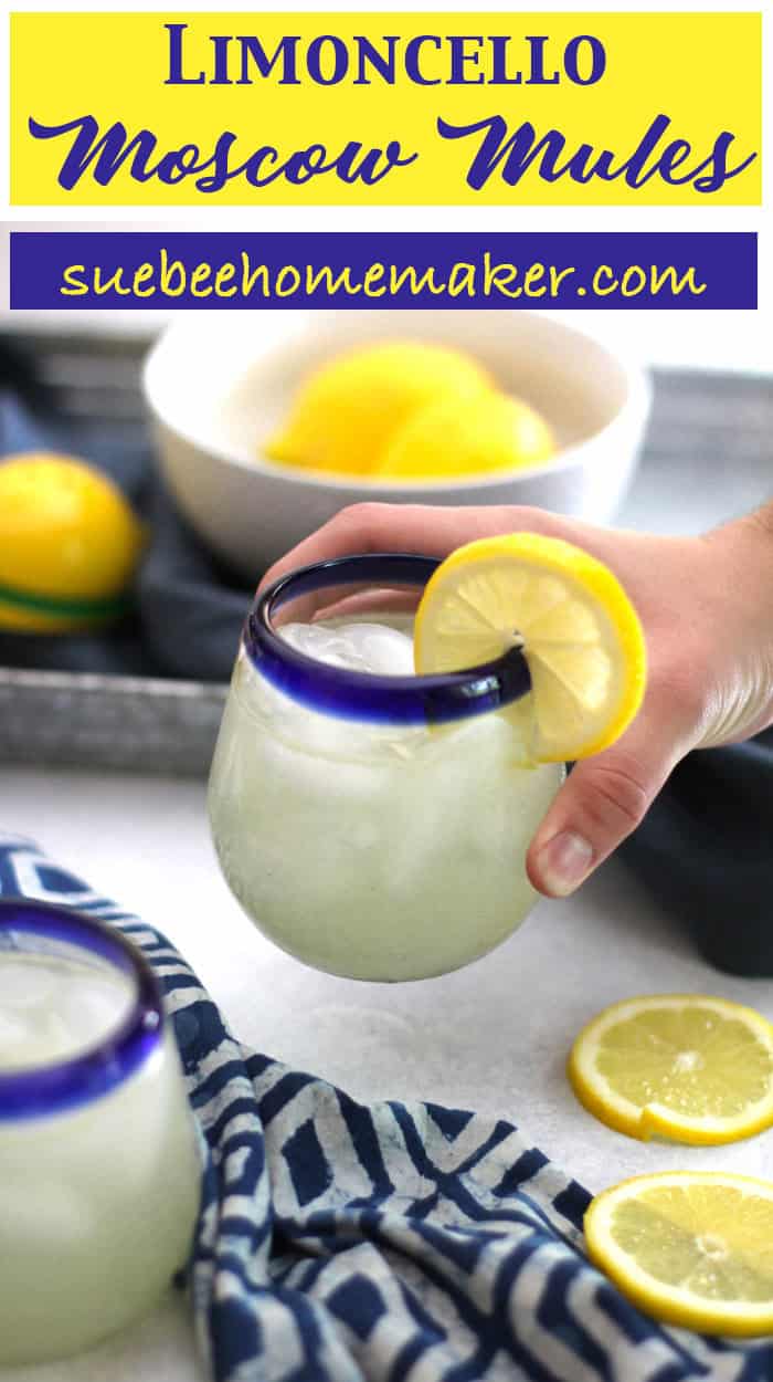 A hand holding a limoncello Moscow mule, with ingredients in the background.
