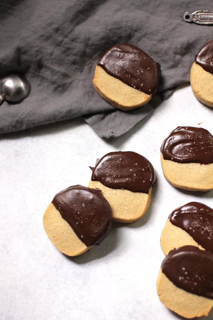 Overhead view of shortbread cookies dipped in chocolate, on a white background with gray napkin.