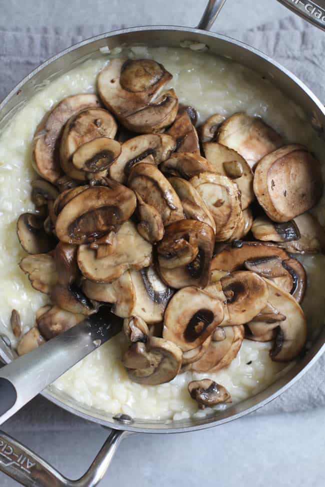 A pan of creamy risotto with sautéed mushrooms.
