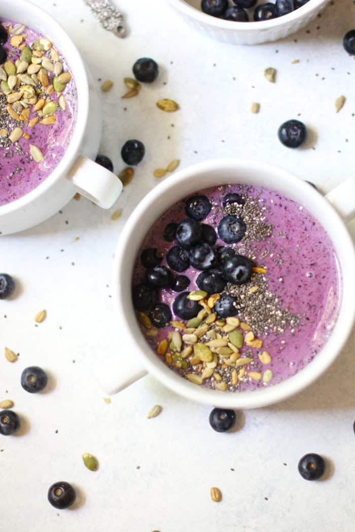 Two blueberry smoothie bowls on a white background.