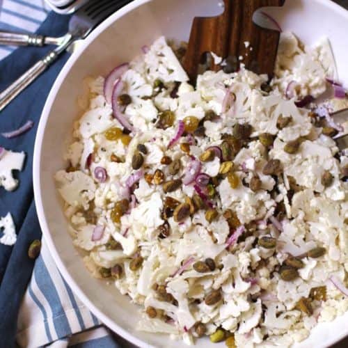 A bowl of shaved cauliflower salad with pistachios on top.