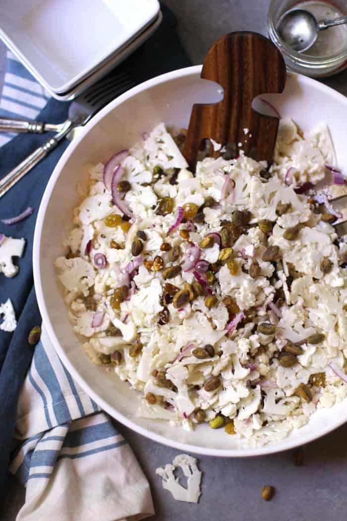 A bowl of shaved cauliflower salad with pistachios on top.