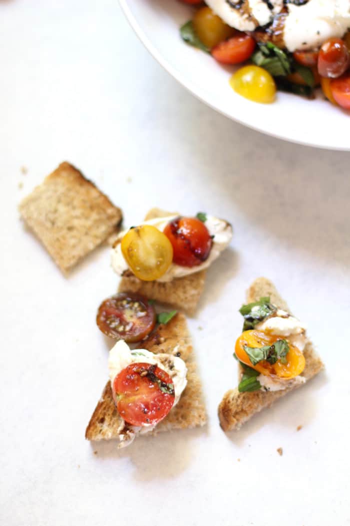Several wedges of bread with balsamic glazed tomatoes and burrata.