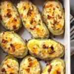 Overhead shot of twice baked potatoes in a rectangular white casserole dish, showing the lower left corner and the white handle.