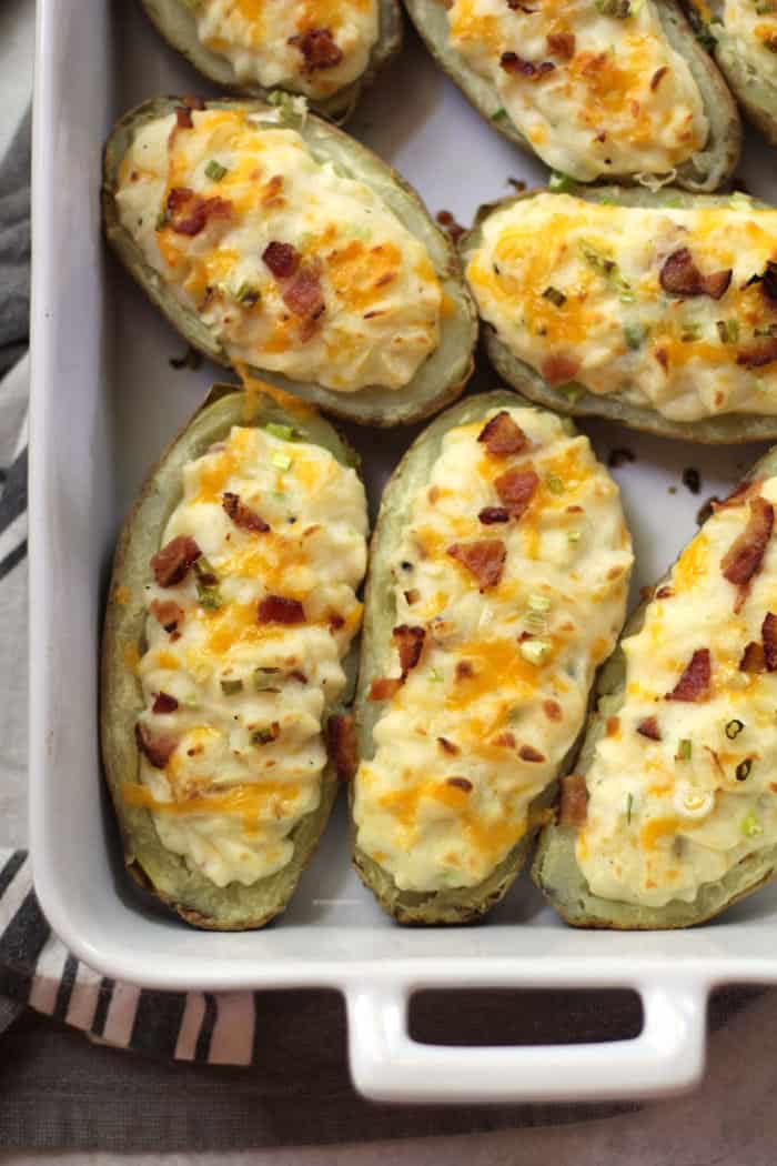 Overhead shot of twice baked potatoes in a rectangular white casserole dish, showing the lower left corner and the white handle.