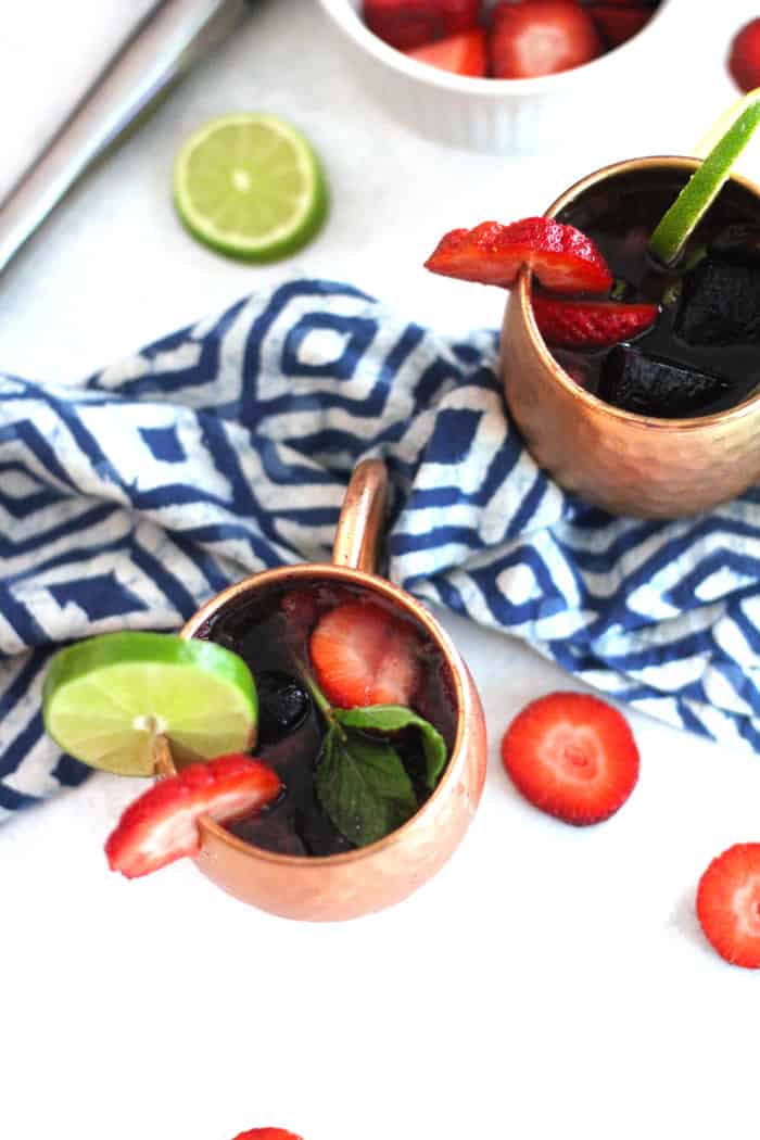 Overhead view of two copper mugs of strawberry Mexican mules.