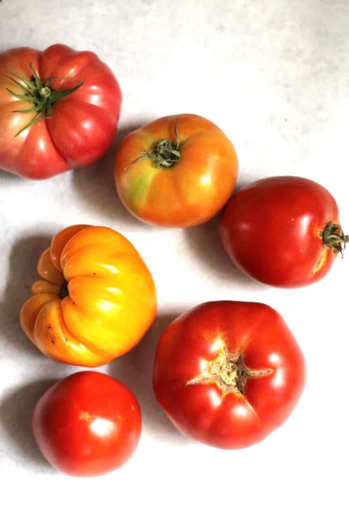 Several home grown tomatoes on a white surface.