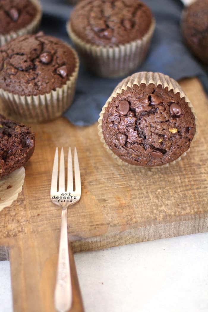 Close up shot of chocolate zucchini muffins, with a fork on a wooden board.