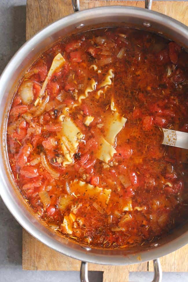Overhead shot of a large stock pot of lasagna soup, on a wood board.