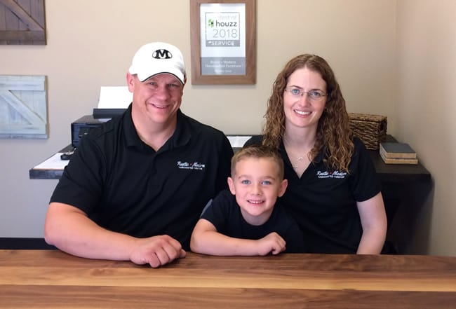 Picture of owners, Ken and Emily Williams and their son, sitting at a wood table in their office.