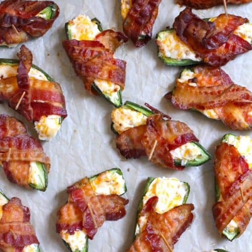 Overhead shot of just-baked bacon wrapped jalapeño poppers on a baking sheet with parchment paper.